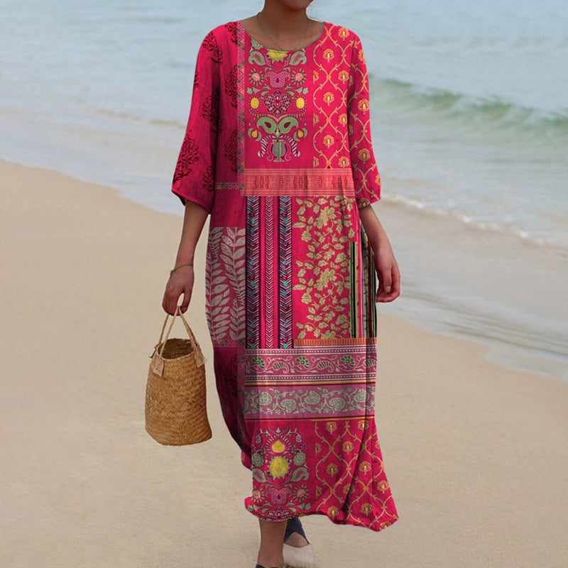 Women's pink patchwork boho maxi dress with floral and geometric patterns — front view on beach