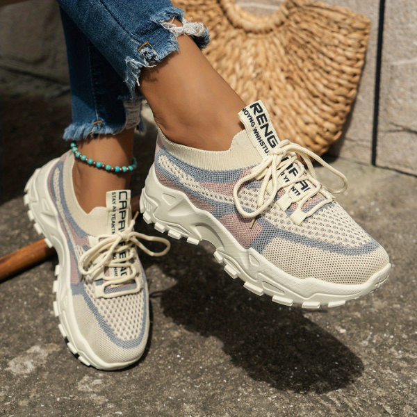 Chunky beige mesh sneakers with pastel striped details and thick soles — side view on model