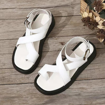 White platform sandals with black soles and ankle straps on wooden surface — top-down view