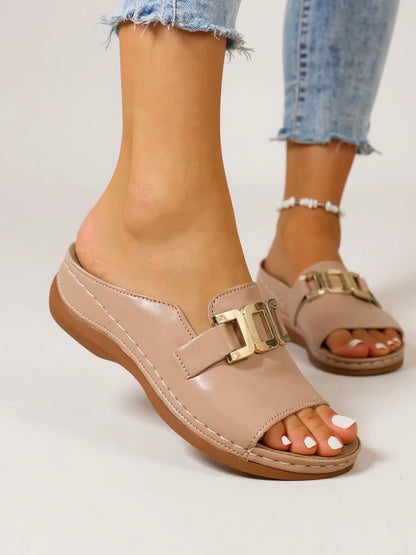 Women's nude cushioned slide sandals with gold buckle detail — front angled view