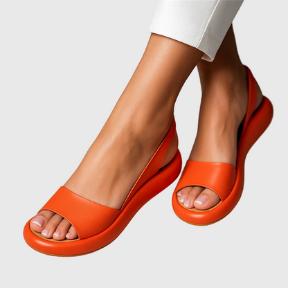 Orange open-toe slip-on flat sandals with wide strap and curved sole — side angle view