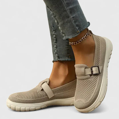 Women's beige mesh slip-on sneakers with buckle strap detail — side view on model