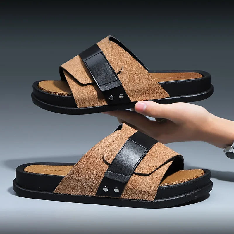 Two-tone beige and black cushioned slide sandals with crossed straps — held in hand showing pair stacked