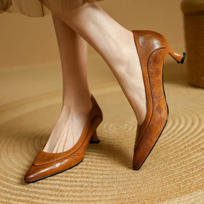 Tan leather pointed toe kitten heel pumps with textured detail — side view on model's feet
