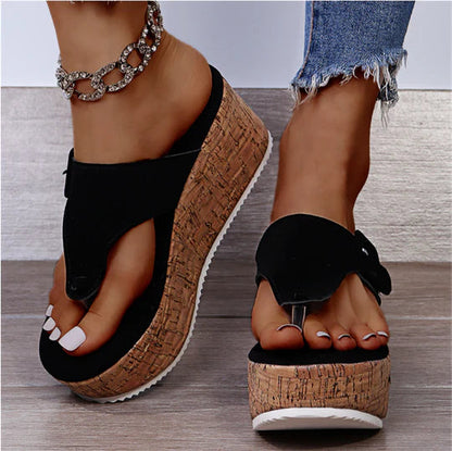 Black bow flip-flop sandals with cork wedge platform — angled front view on model