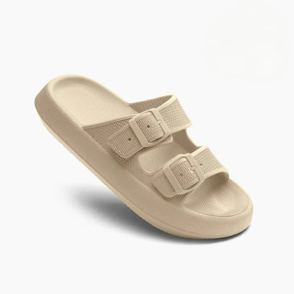 Beige two-strap buckle slide sandals with textured footbed — three-quarter angled view