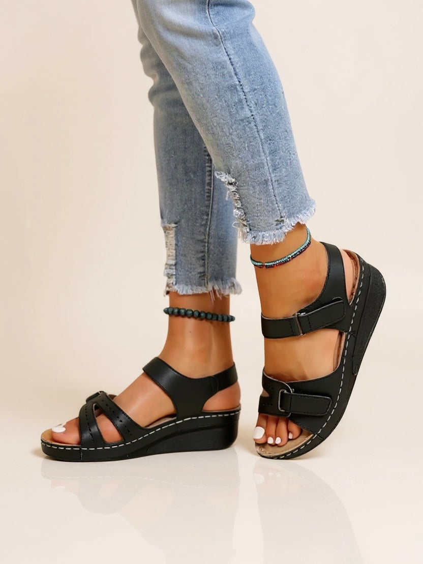 Women's black wedge sandals with adjustable buckle straps and white contrast stitching — side view
