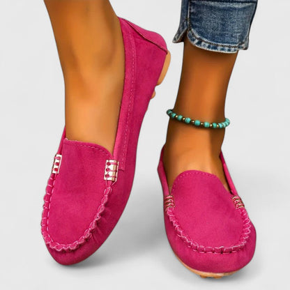 Women's hot pink suede slip-on loafers with white contrast stitching — front angled view
