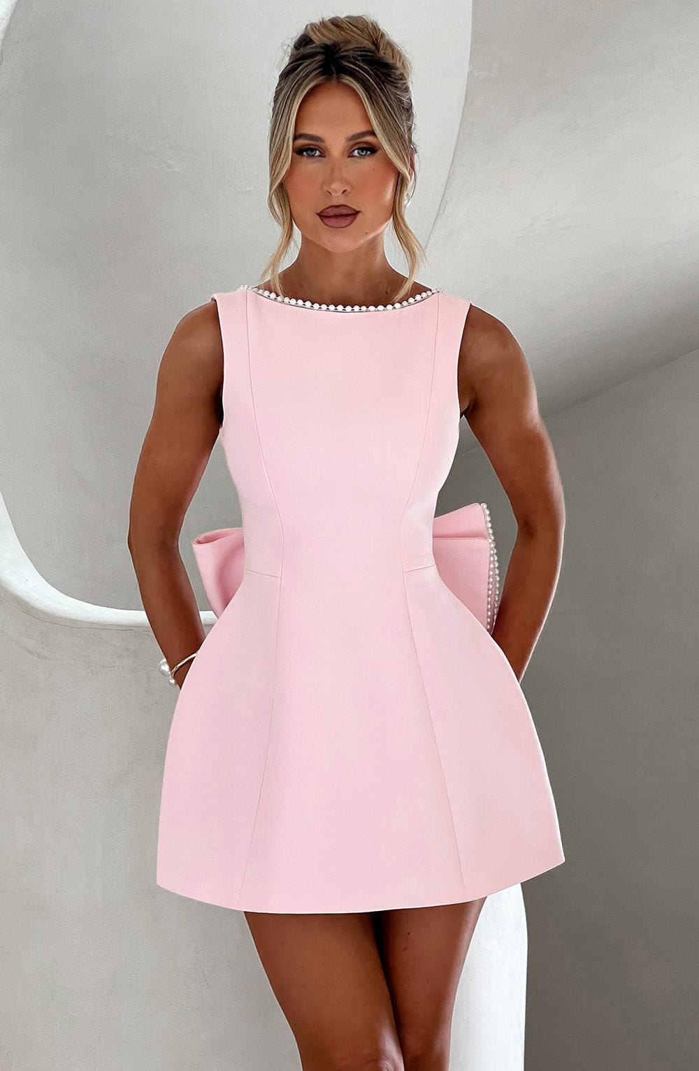 Pink A-line mini dress with pearl neckline detail and pockets — front view on model