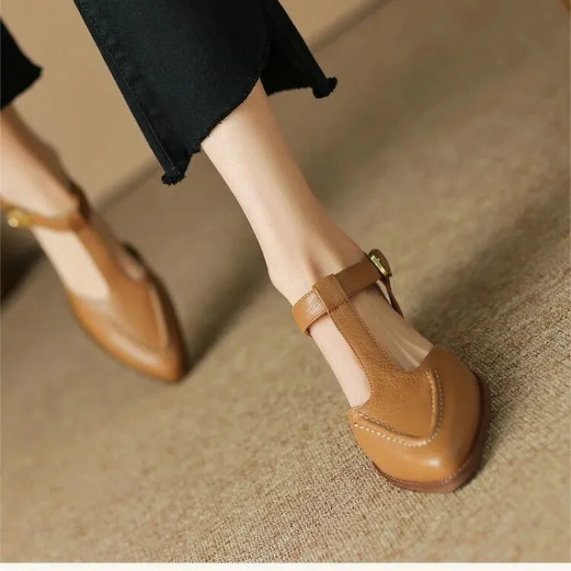 Women's tan T-strap buckle shoes with pointed toe and low heel — front angled view