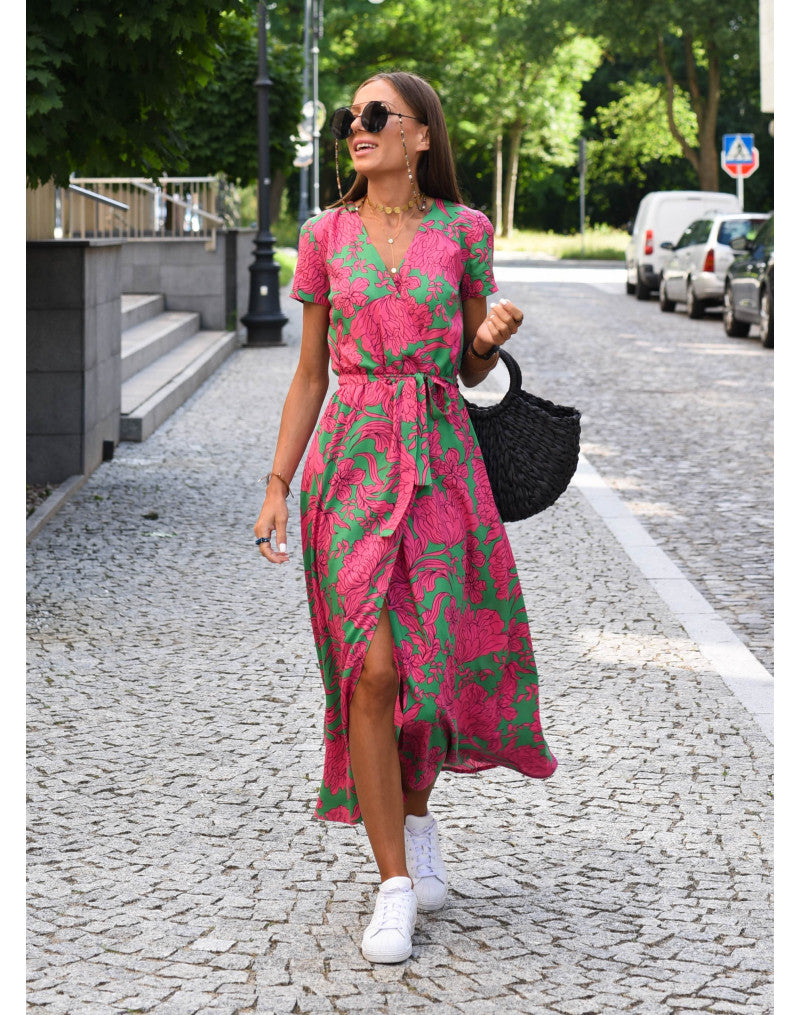 Woman in pink and green floral print maxi dress with belt and sneakers — full body front view