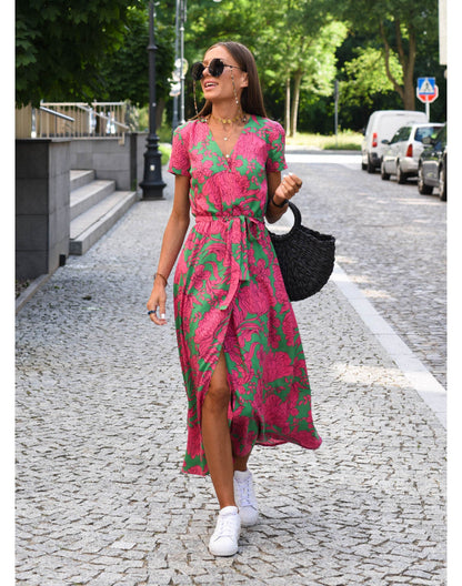 Woman in pink and green floral print maxi dress with belt and sneakers — full body front view