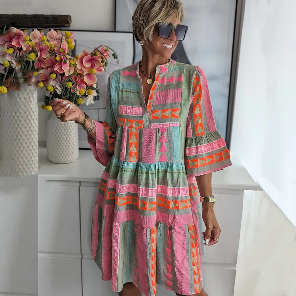 Colorful geometric patterned tiered midi dress with bell sleeves — front view on model