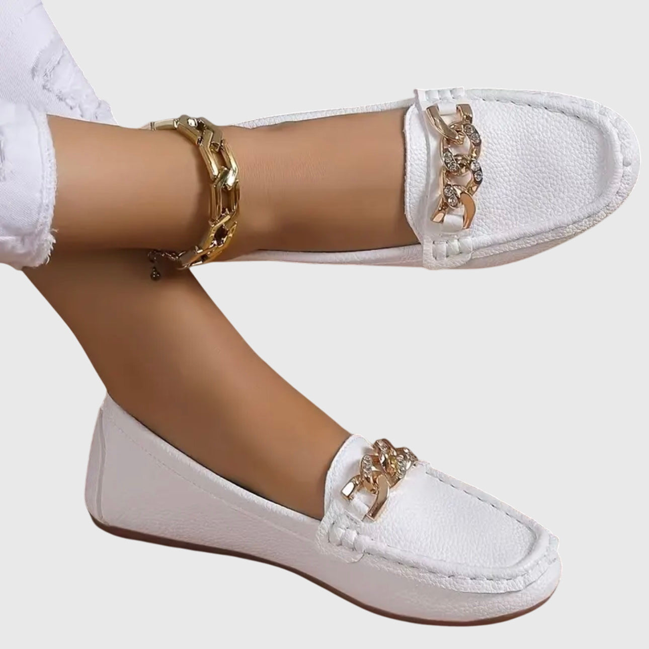 White leather loafers with gold chain detail on top — angled front view on model