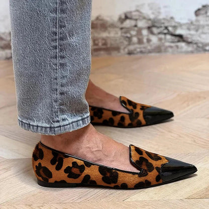 Leopard print pointed-toe flat shoes with black patent cap toe — side view on wood floor