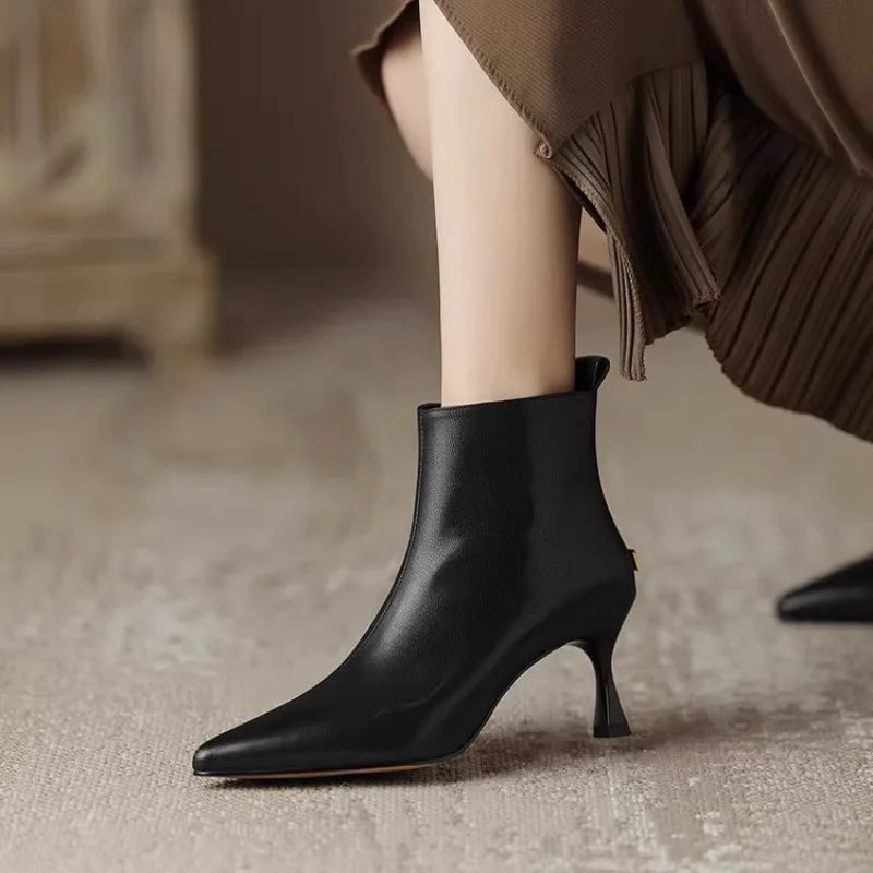 Black leather kitten heel ankle boots with pointed toe on model — side view