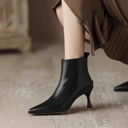 Black leather kitten heel ankle boots with pointed toe on model — side view
