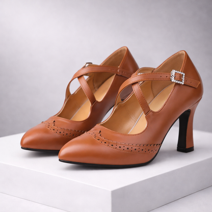 Women's tan leather T-strap block heels with brogue detailing and rhinestone buckle — three-quarter front view