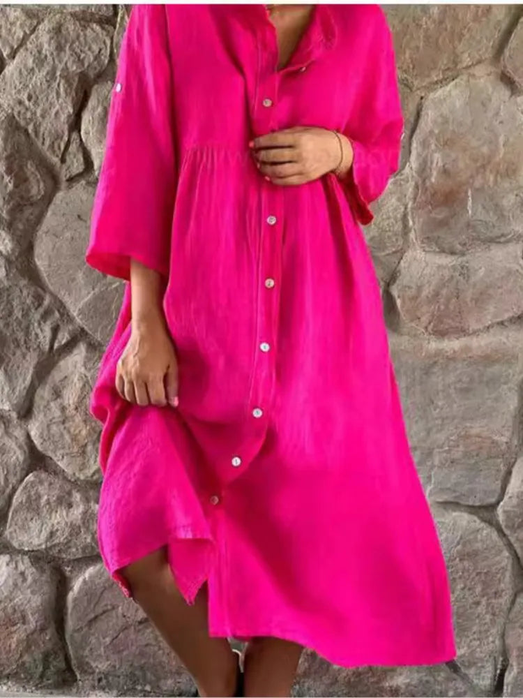Hot pink button-down midi shirt dress with 3/4 sleeves — front view on model against stone wall