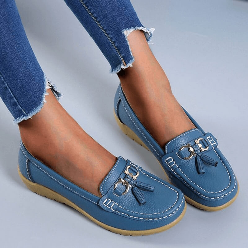 Women's blue leather tassel loafers with white contrast stitching — front three-quarter view on model