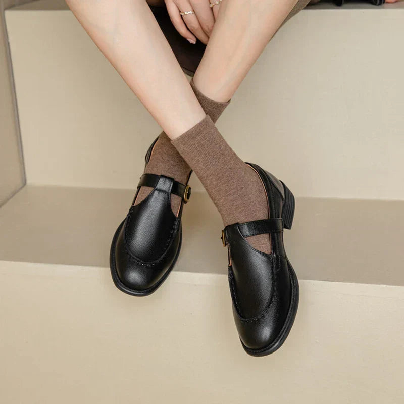 Black leather T-strap Mary Jane shoes with brown ribbed socks — front angled view