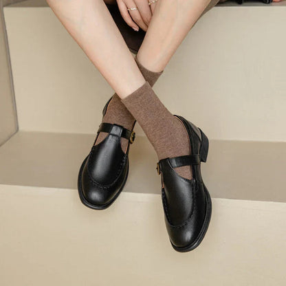 Black leather T-strap Mary Jane shoes with brown ribbed socks — front angled view