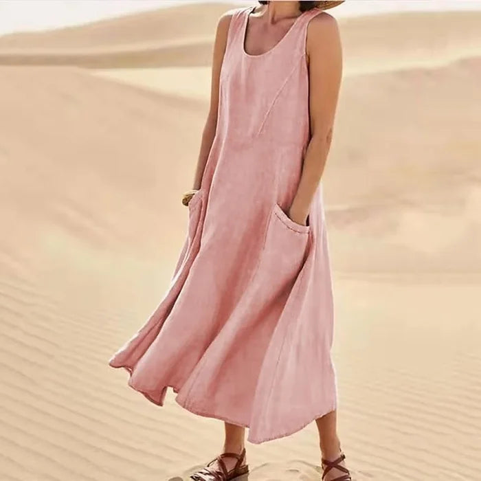 Pink sleeveless midi dress with pockets on model in desert — front angled view