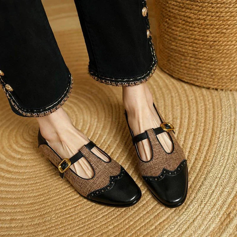 Women's two-tone brown and black T-strap Mary Jane shoes with brogue detail — front view on feet