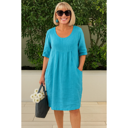 Woman wearing turquoise linen midi dress with pockets and half sleeves — front view