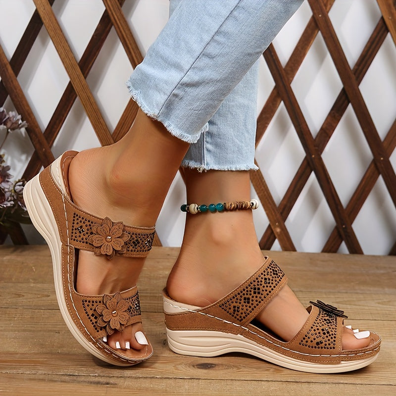 Women's brown perforated wedge slides with floral embellishments — side view on model wearing light jeans