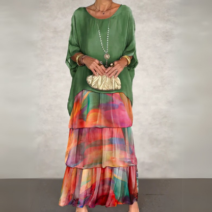 Sage green tunic top over rainbow plaid tiered maxi skirt with gold accessories — front view