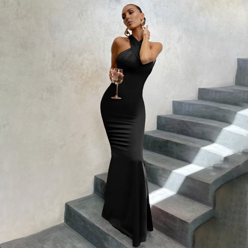 Black halter neck bodycon maxi dress with fishtail hem — front view on model holding wine glass