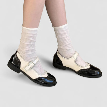 Black and white orthopedic Mary Jane shoes with decorative perforations — front three-quarter view