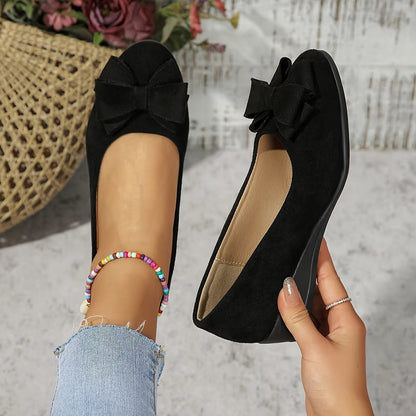 Black bow-detailed round-toe ballet flats — worn on foot and held in hand view
