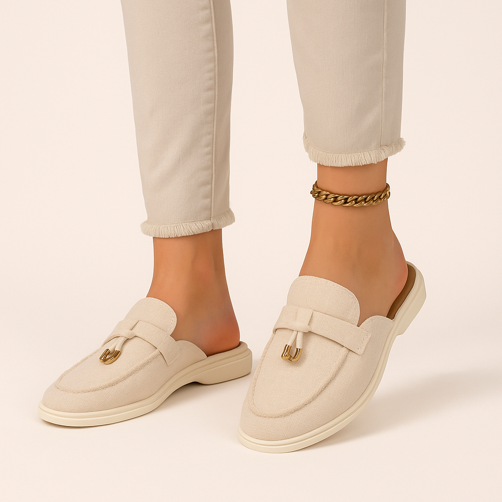 Women's beige backless loafer mules with gold hardware detail — front angled view