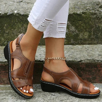 Brown leather cutout sandals with ankle chain detail on model — side view