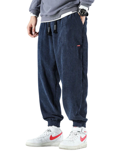 Navy blue corduroy jogger pants with elastic cuffs and drawstring waist — front three-quarter view