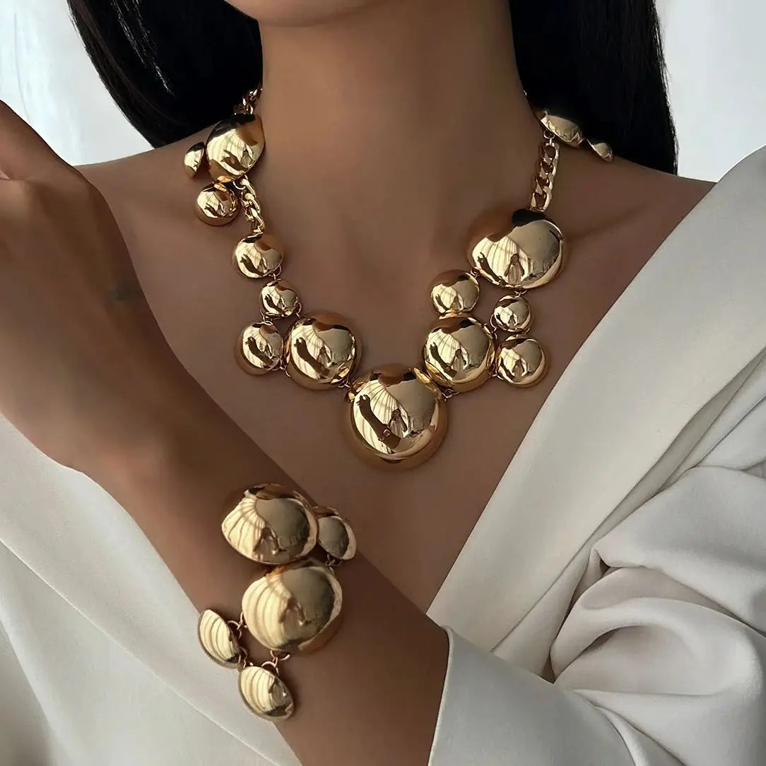 Gold orb statement necklace and bracelet set on model — front view