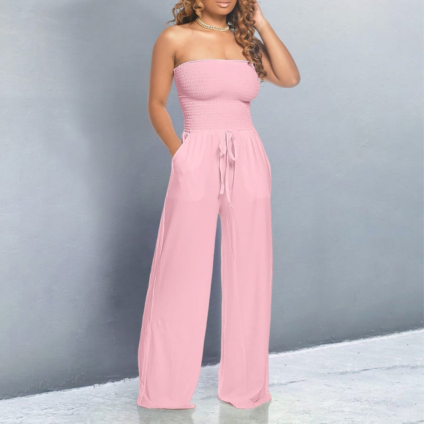 Pink strapless smocked jumpsuit with wide-leg pants and tie waist — front view