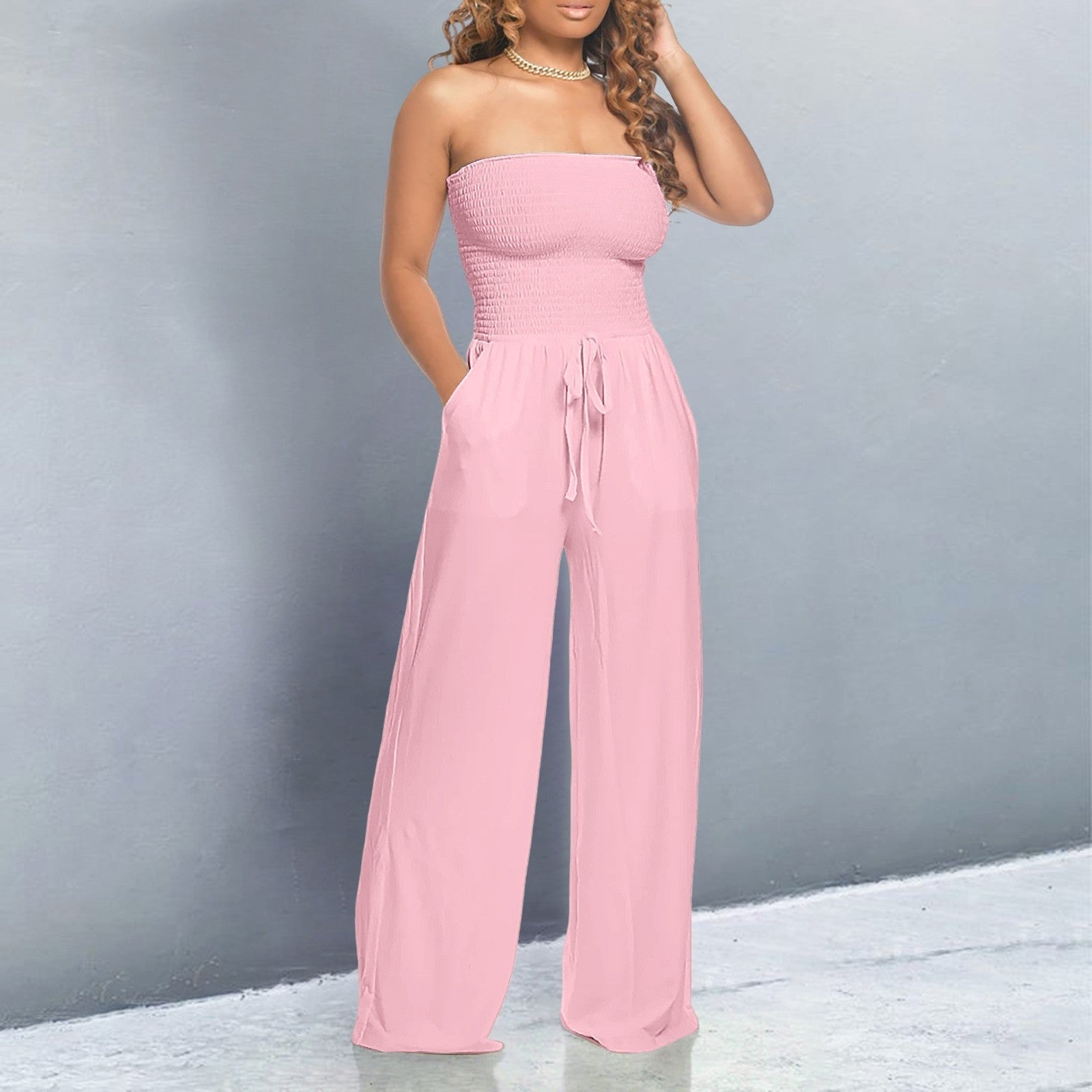 Pink strapless smocked jumpsuit with wide-leg pants and tie waist — front view