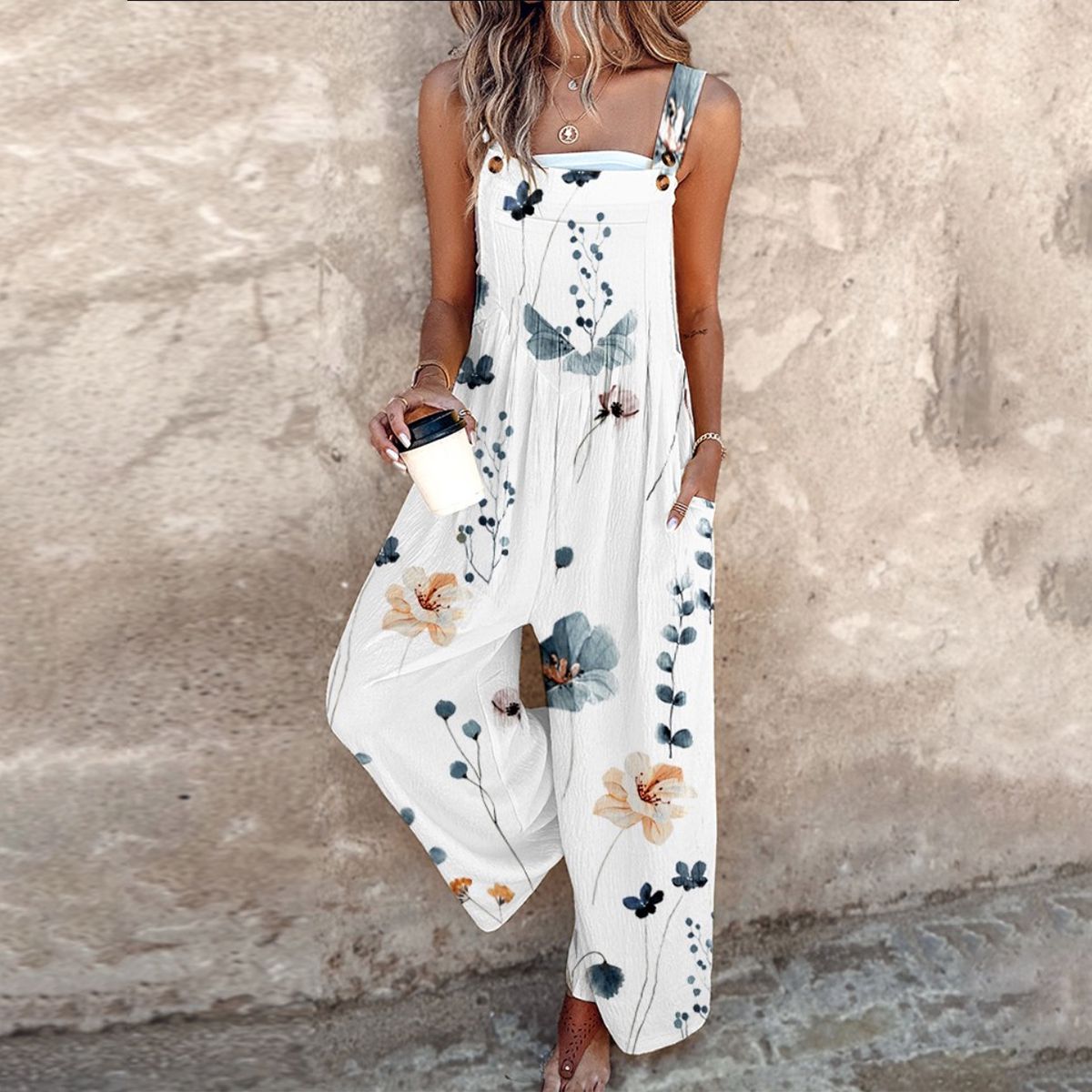 Women's white floral print wide-leg jumpsuit with adjustable straps and button details — front view