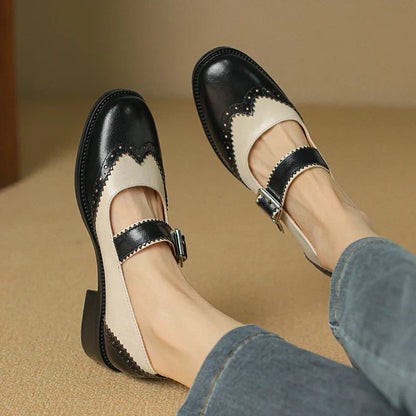 Black and white leather Mary Jane brogue shoes with T-strap buckle — angled front view on model
