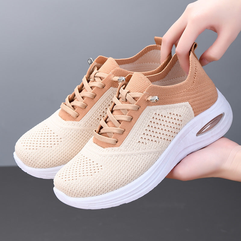 Women's beige mesh sneakers with tan accents and air cushion sole held by hand — side angle view