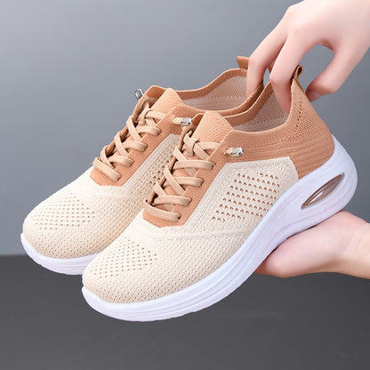 Women's beige mesh sneakers with tan accents and air cushion sole held by hand — side angle view