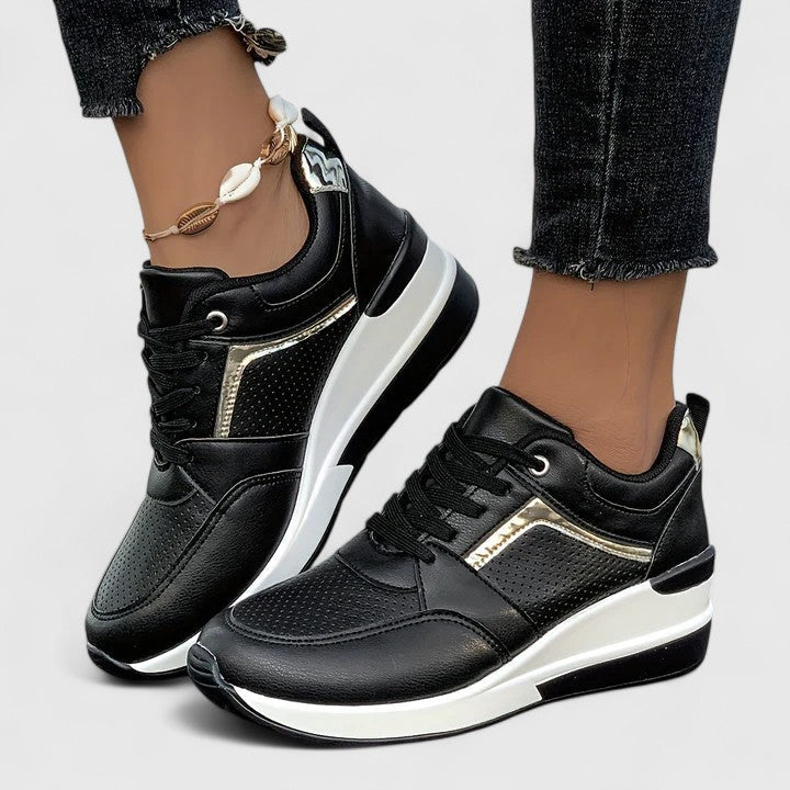 Black leather orthopedic sneakers with gold accent and platform sole — side view on model