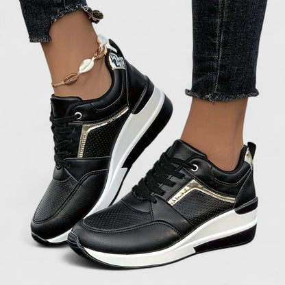 Black leather orthopedic sneakers with gold accent and platform sole — side view on model