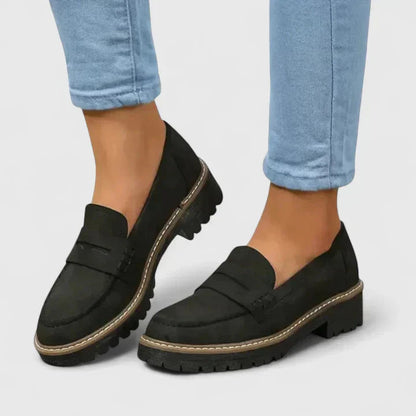 Black slip-on loafers with chunky lug soles worn with light blue jeans — front angled view