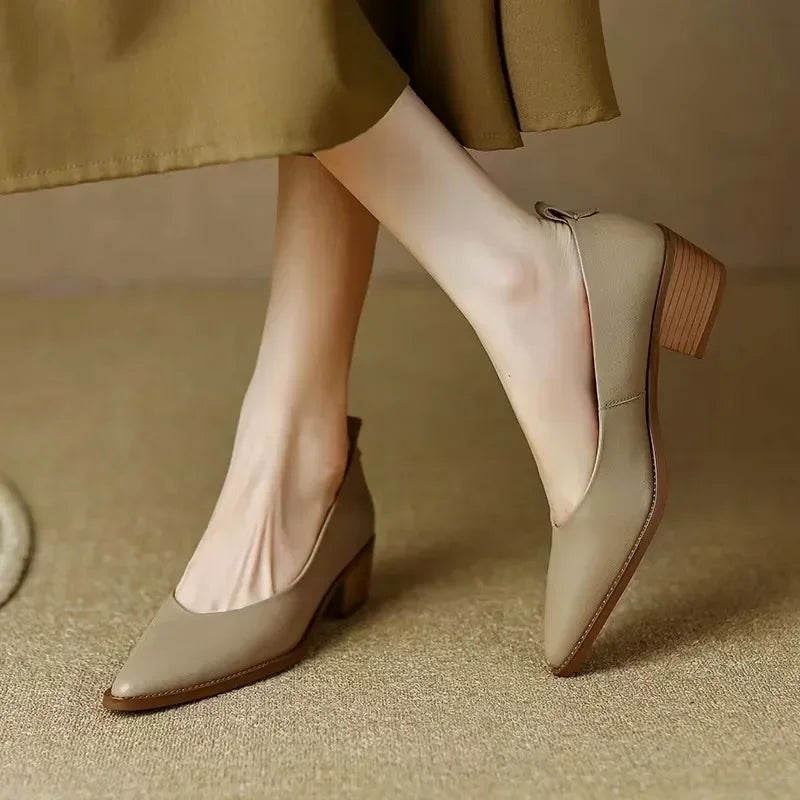 Beige pointed toe block heel pumps with bow detail — side angle view on model wearing white socks